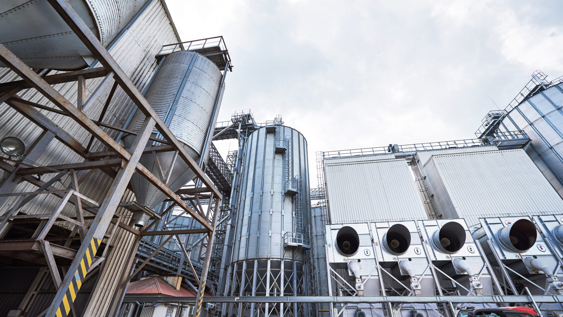 Agricultural Silos. Building Exterior. Storage and drying of grains, wheat, corn, soy, sunflower against the blue sky with white clouds
